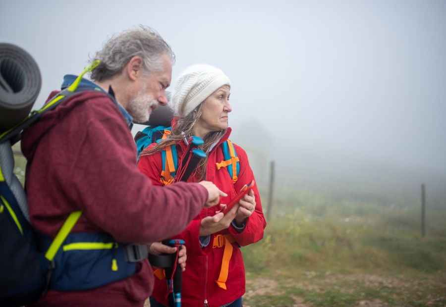 Two hikers in the fog checking a phone for signal