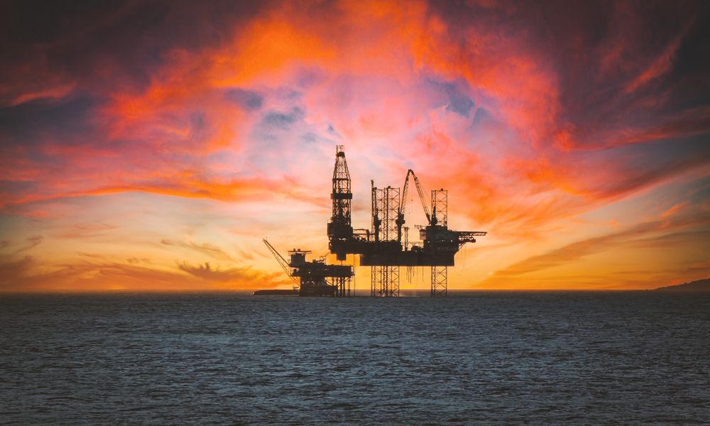 Offshore oil platform silhouetted against a sunset